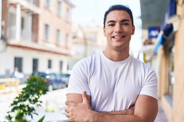 Sticker - Young hispanic man standing with arms crossed gesture at street