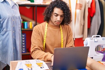 Sticker - Young latin man tailor using laptop at atelier