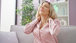 © Krakenimages.com - Young blonde woman sitting on sofa suffering for cervical pain at home