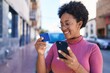 © Krakenimages.com - African american woman using smartphone and credit card at street