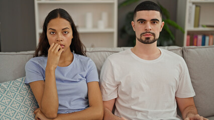 Poster - Upset beautiful couple in disagreement, silently looking at each other, sitting on the sofa in their home's living room