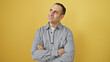 © Krakenimages.com - Portrait of a contemplative young hispanic man with crossed arms against a vibrant yellow background