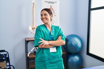 Canvas Print - Young beautiful hispanic woman pysiotherapist smiling confident standing with arms crossed gesture at rehab clinic