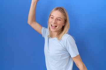 Poster - Young caucasian woman wearing casual blue t shirt dancing happy and cheerful, smiling moving casual and confident listening to music