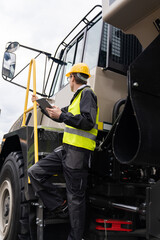 Poster - Engineer with tablet computer stands on the stairs to the cab of a truck..