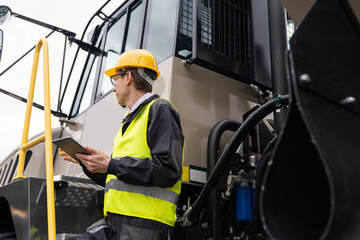 Poster - Engineer with tablet computer stands on the stairs to the cab of a truck..