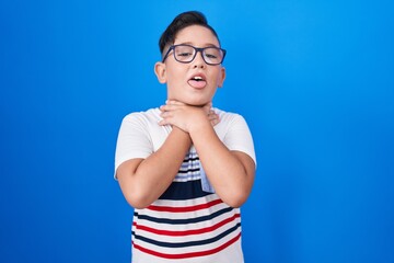 Poster - Young hispanic kid standing over blue background shouting and suffocate because painful strangle. health problem. asphyxiate and suicide concept.