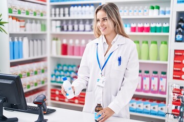 Canvas Print - Young blonde woman pharmacist smiling confident holding medication bottles at pharmacy