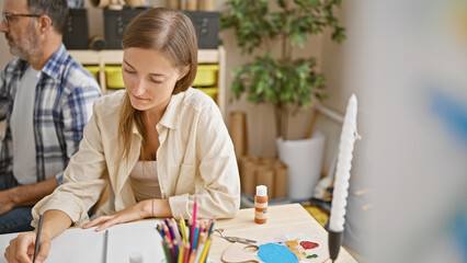 Wall Mural - Two focused artists, a woman and man, drawing on canvas and paper, unleashing creativity at their indoor art studio class