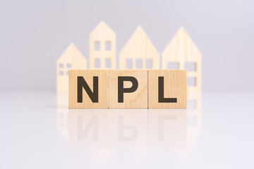 Wall Mural - NPL text made of wooden cubes with a small wooden model houses. the image symbolizes the strategic evaluation and monitoring of Non Performing Loans in real estate or business