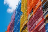 Fototapeta  - Construction site. Construction, renovation of high-rise residential building, office. Colorful hoarding on construction site, with building outline emerging behind it. Safety net covering building