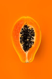 Fototapeta  - Papaya fruit on orange, yellow background. Half of fresh organic Papaya exotic fruit close up. Vertical image. Top view