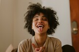 Fototapeta  - A woman sticks out her tongue with a funny expression, hands clasped.
