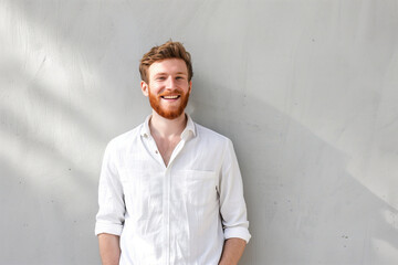 Wall Mural - Confident Young Man with a Warm Smile Standing Against a Textured Grey Wall, Exuding Casual Elegance in Sunlight