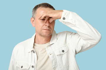 Poster - Ill mature man blowing nose on blue background