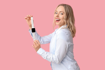 Wall Mural - Pretty young woman with modern smartwatch on pink background