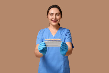 Wall Mural - Young female dentist with dental shade guide on beige background