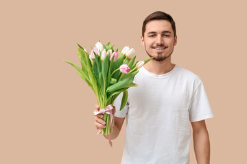 Poster - Happy young man with bouquet of beautiful tulips on beige background. International Women's Day