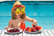 © Volodymyr - Healthy food. Outdoor leisure activity with kids by swimming pool. Summertime. Summer child by the pool eating fruit and drinking lemonade cocktail. Summer kids. Little kid boy relaxing in a pool.