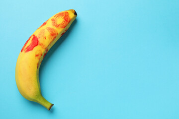 Wall Mural - Banana with red lipstick marks on light blue background, top view with space for text. Sex concept