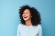 Portrait of a beautiful young african american woman laughing against blue background