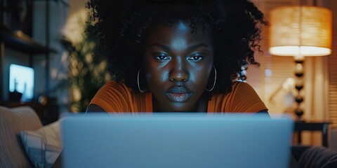 African American Female developer codes on her laptop while working from home (wfh) at night