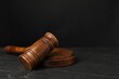 Wooden gavel on dark textured table, closeup. Space for text