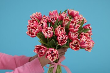 Wall Mural - Woman holding beautiful bouquet on light blue background, closeup