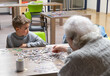 Elderly woman doing a puzzle with her great-grandson in a nursing home
