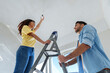 © Westend61 - Smiling man helping woman in installing light bulb at home