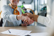© Westend61 - Smiling woman shaking hands with car salesperson at desk
