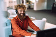 © Westend61 - Happy businessman wearing headset and working on computer in office