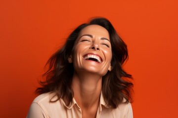 Poster - Portrait of a happy young woman laughing and looking up on orange background