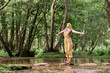 © Westend61 - Young woman standing with arms outstretched in forest