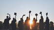 © Довидович Михаил - Silhouettes of college graduates waving their caps at sunset.