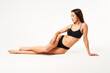 © GVS - Young beautiful woman with perfect body in black underwear sitting on floor posing on studio