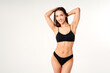 © GVS - Smiling sporty woman in black underwear posing on white studio background