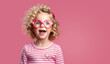 Little blonde child with heart shaped eye glasses on pink background with copy space. Happy childhood, Valentines day celebration holidays.