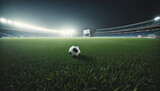 Fototapeta Sport - Soccer ball on the grass of a soccer stadium illuminated by the floodlights of the stands