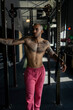 Chico joven musculado y tatuado posando en gimnasio sin camiseta