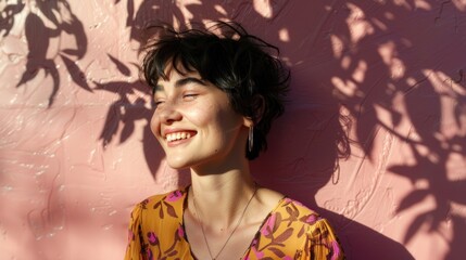 Wall Mural - Smiling woman with short hair wearing a floral top leaning against a pink textured wall with shadows of leaves.