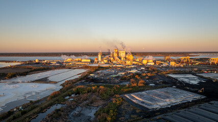 Early morning light bathes a paper mill in Brunswick, Georgia, with storage and industrial activity.