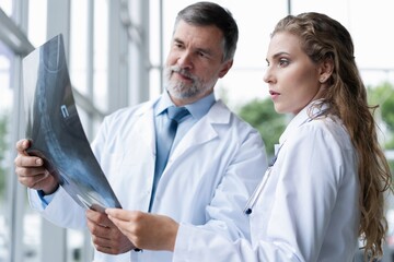 Wall Mural - Professional medical team with doctors and surgeon examining patient's x-ray image, discussing and pointing.