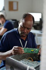Poster - Experienced African American engineer of repair service office looking at computer motherboard while identifying technical problem