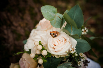 Wall Mural - A pair of gold wedding rings on a bouquet of white flowers. Two gold rings on a bouquet of roses