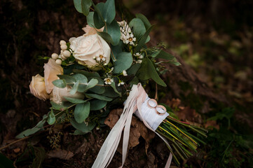 Wall Mural - A pair of gold wedding rings on a bouquet of white flowers. Two gold rings on a bouquet of roses