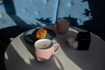 two cups of coffee latte stand on a light table near a delicious dessert