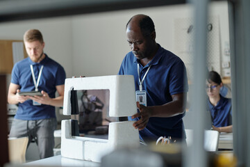 Mature African American engineer of repair service center unpacking computer monitor brought by client before checking it