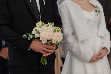 Wall Mural - A beautiful wedding bouquet in the hands of the groom. Bouquet with white roses in the hands of the groom