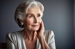 © Elena - Portrait of an elderly woman in a silver dress on a dark gray background, hand propping up her head